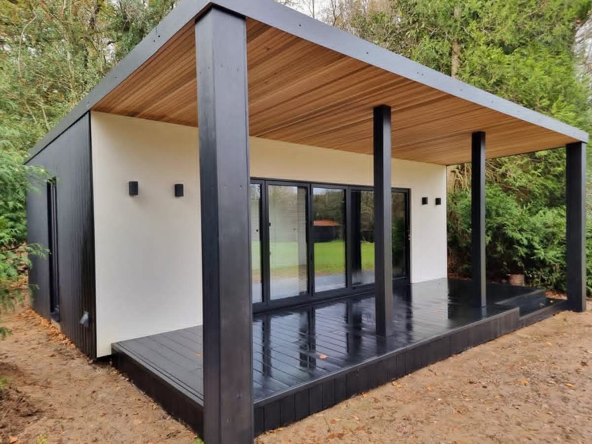 Modulux garden building with white render, a cedar-lined soffit and full-width glazing onto a composite deck